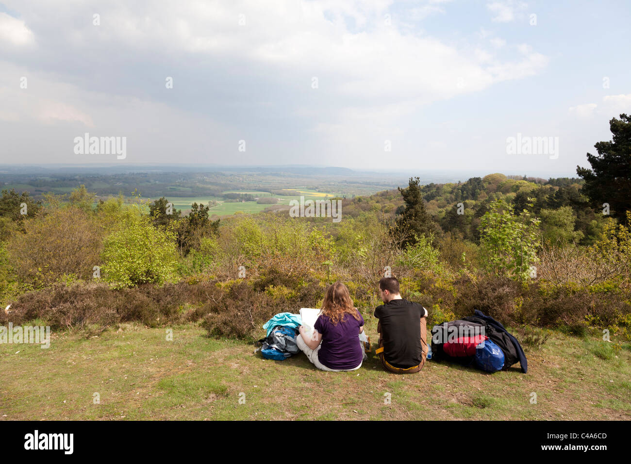 two people, male and female, resting and consulting maps looking out from Gibbet Hill at Hindhead Stock Photo
