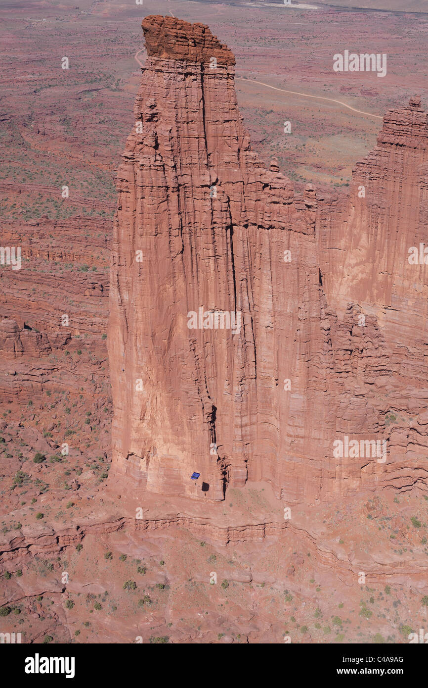 AERIAL VIEW. The Titan of the Fisher Towers. 270-meter-tall rock spire and basejumper with open canopy. Moab, Grand County, Utah, USA. Stock Photo