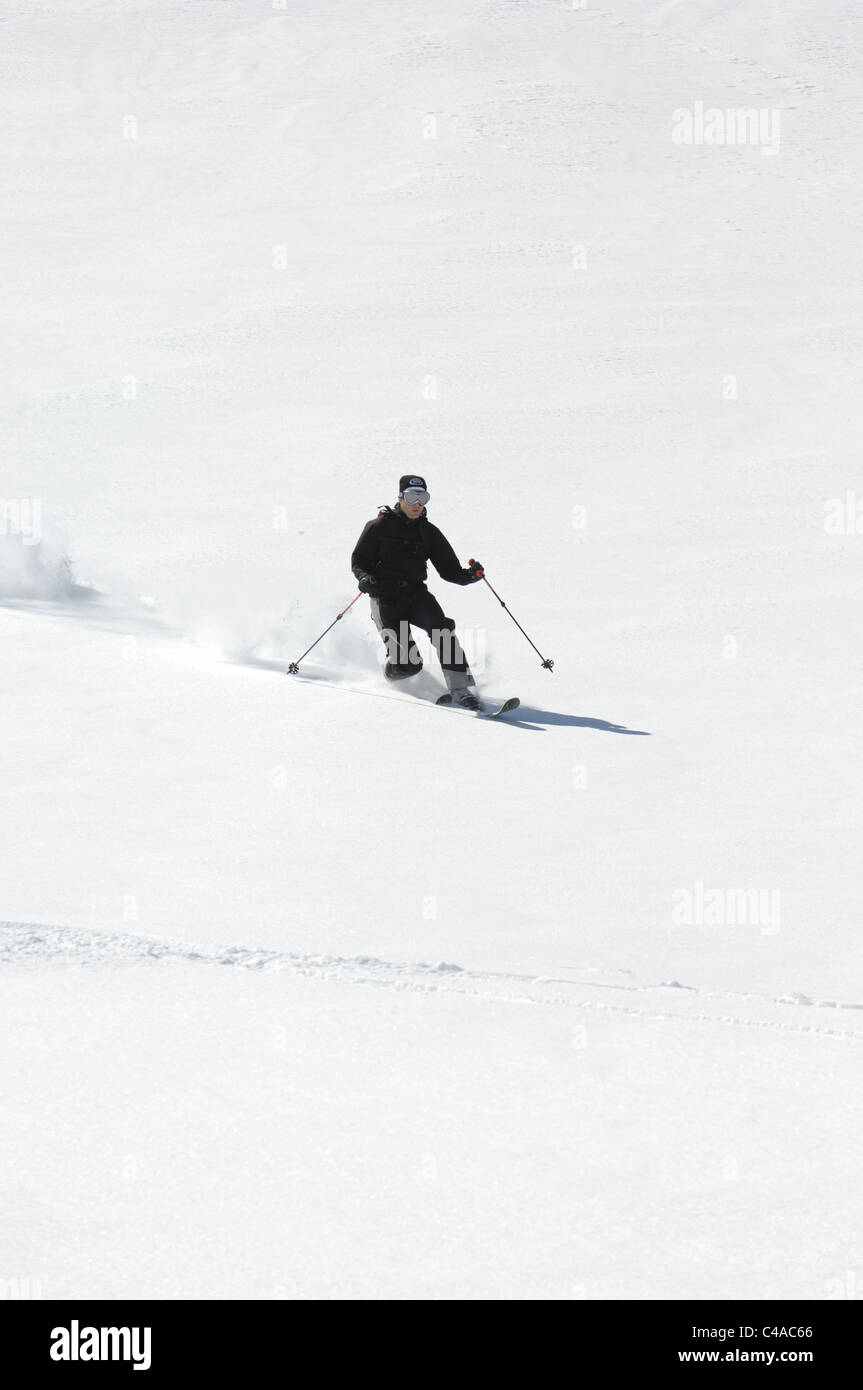 A man telemark skiing in deep fresh powder snow under a clear blue sky in Dizin Iran Stock Photo