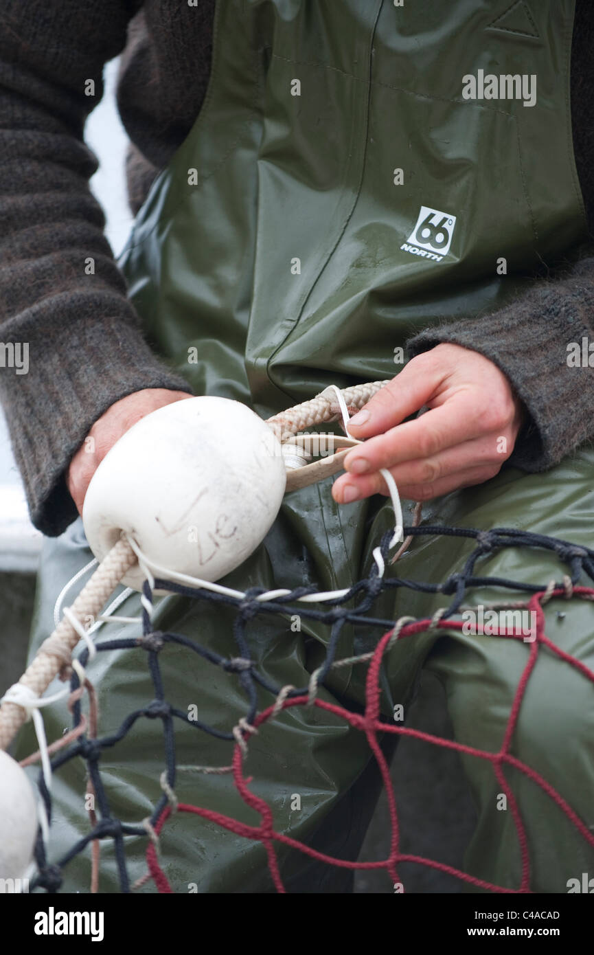 Prince William Sound, Alaska. A salmon fisherman sewing a net used for catching Pink salmon. Stock Photo