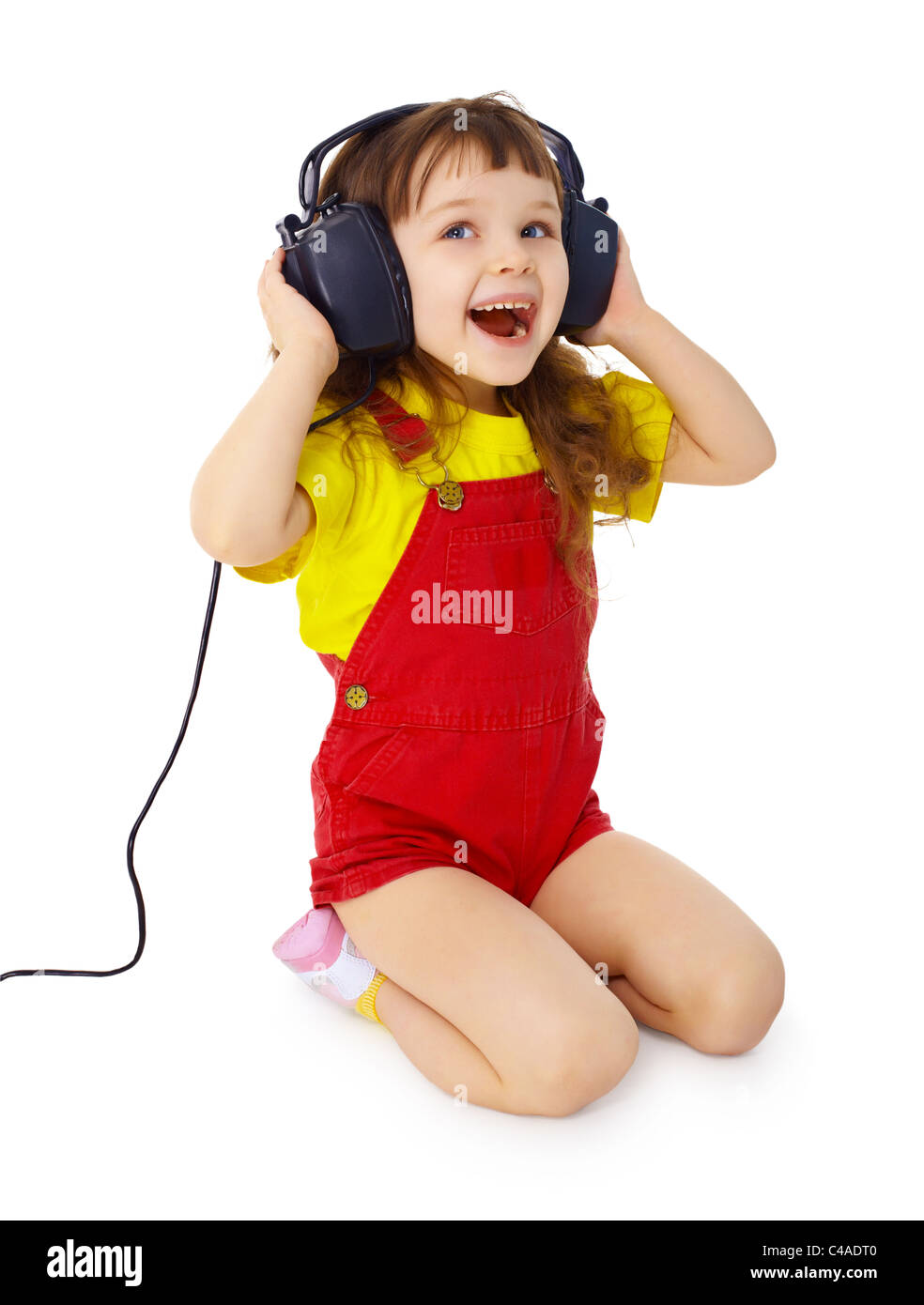 A little girl sitting on a white background with large earpieces Stock ...