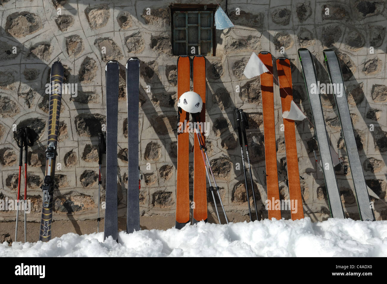 A helmet and skis designed for ski mountaineering with skins on propped up against a stone building in Iran Stock Photo