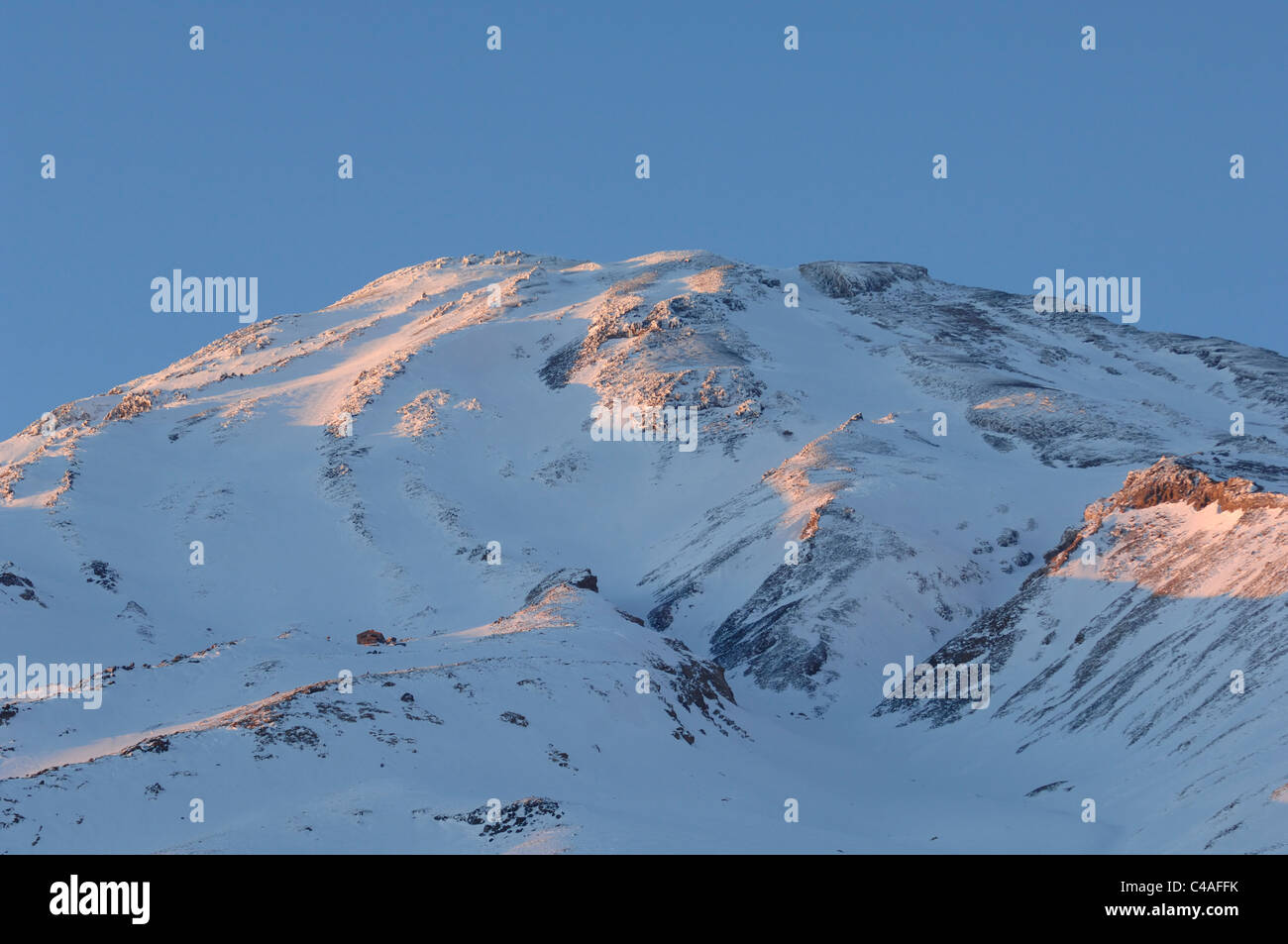 The slopes of a snow covered Mount Damavand in the Alborz mountains of Iran bathed in alpenflow Stock Photo