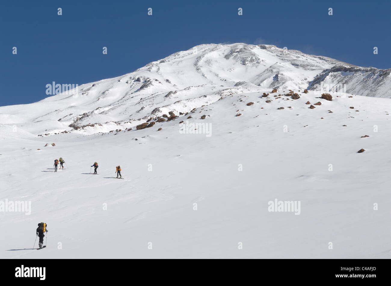 A group of ski mountaineers skinning up hill on the lower slopes of Mount Damavand in Iran Stock Photo