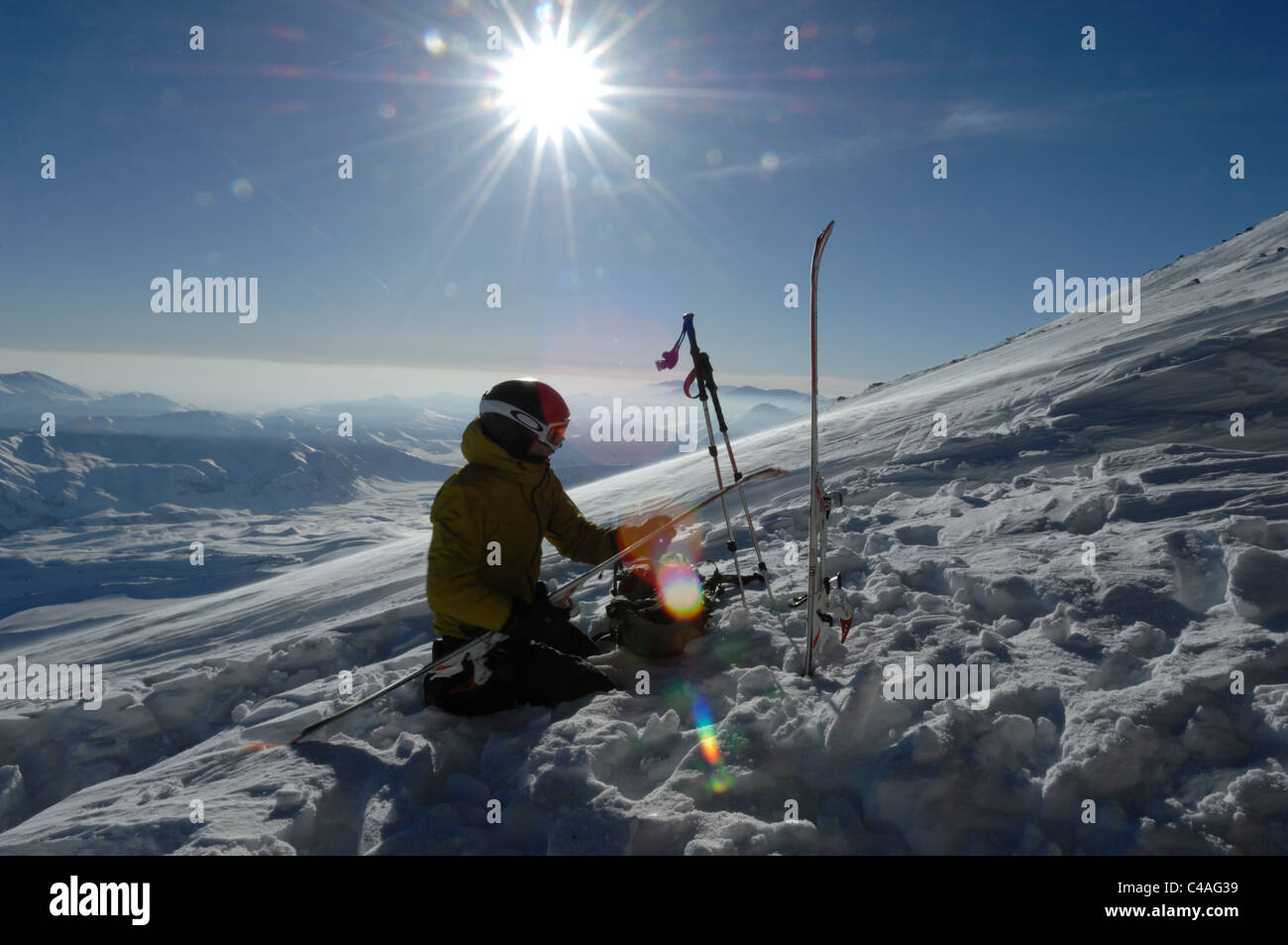 A silhouetted mountaineer fitting ski mountaineering climbing skins on