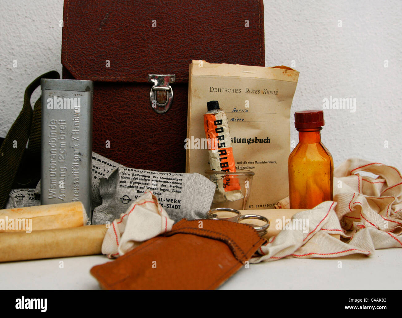 An historical German first aid kit with different tools like compresses,bandages,salve,a notebook of the 'German Red Cross' etc. Stock Photo