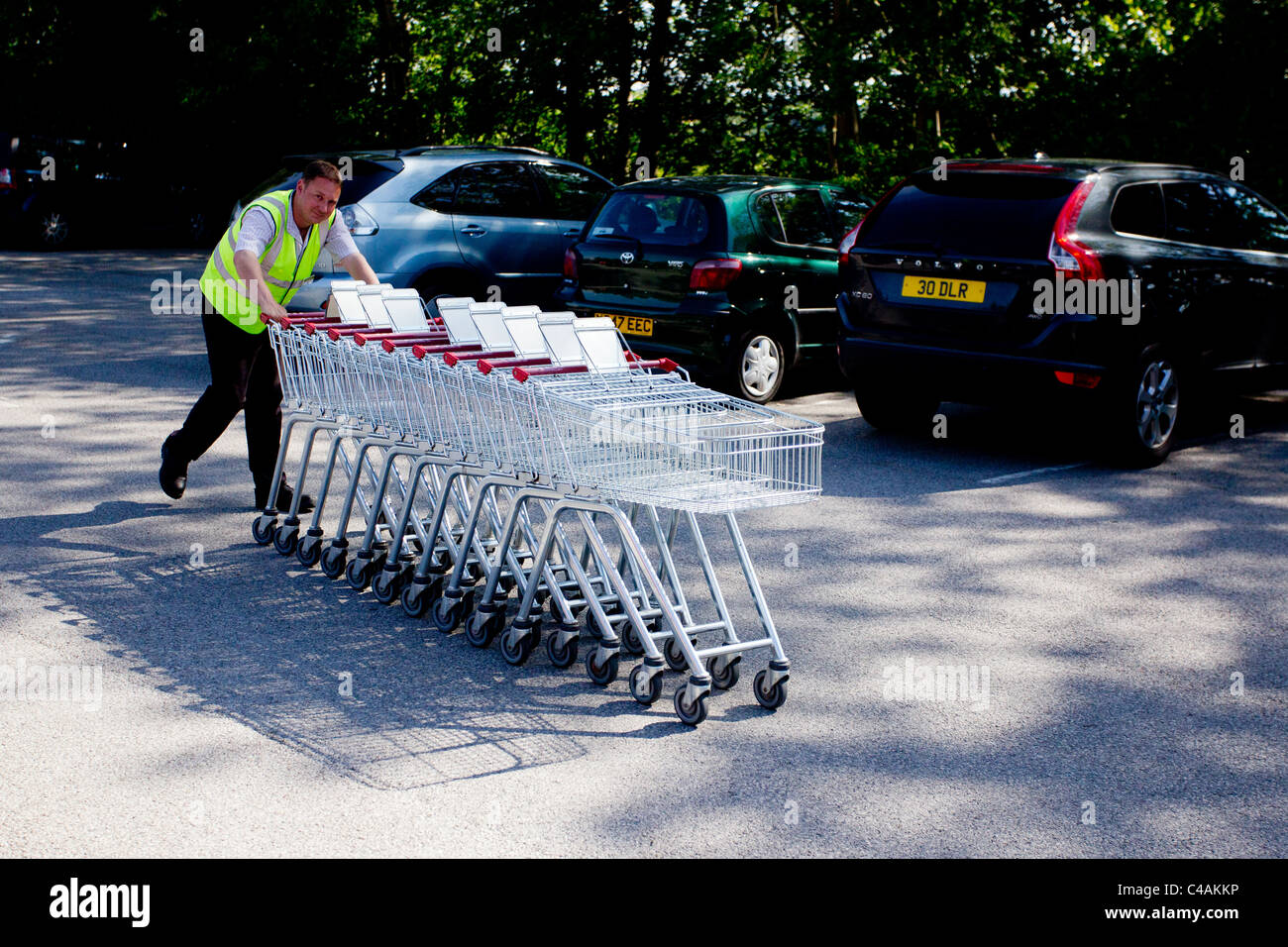 Booths supermarket trolley supervisor pushing a line of trolleys Stock