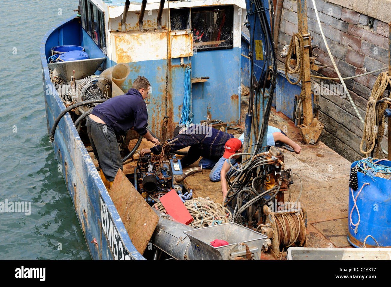 crew of a fishing boat installing the engine to below deck brixham