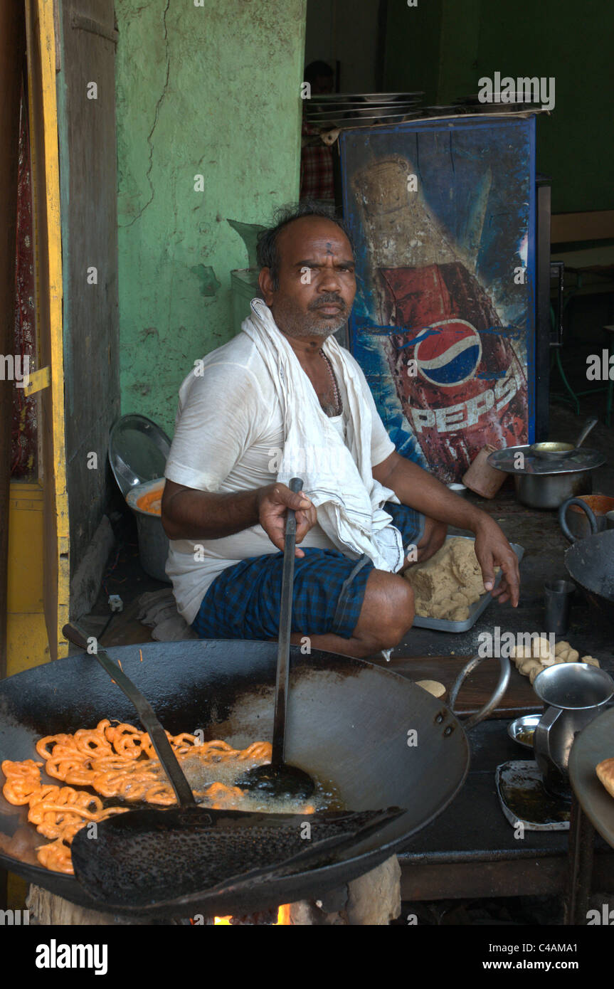 An Indian man frying potato rings in a back street Stock Photo