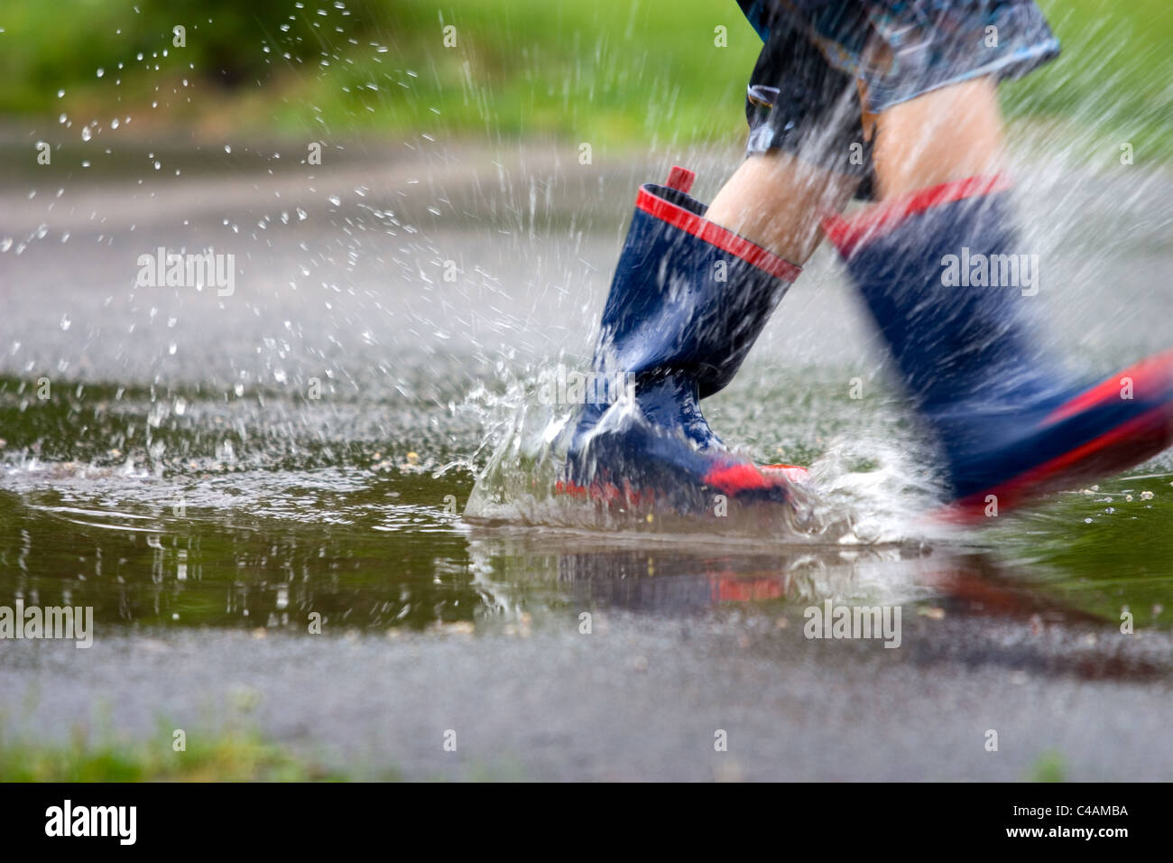 Kids rain boots splashing in a puddle Stock Photo