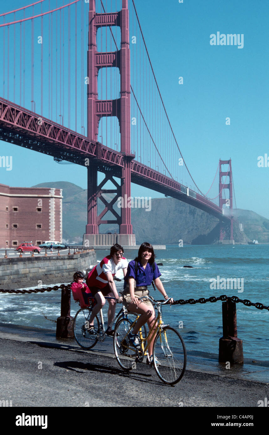 family rides bicycles under Golden Gate bridge at  historic Fort Point Stock Photo