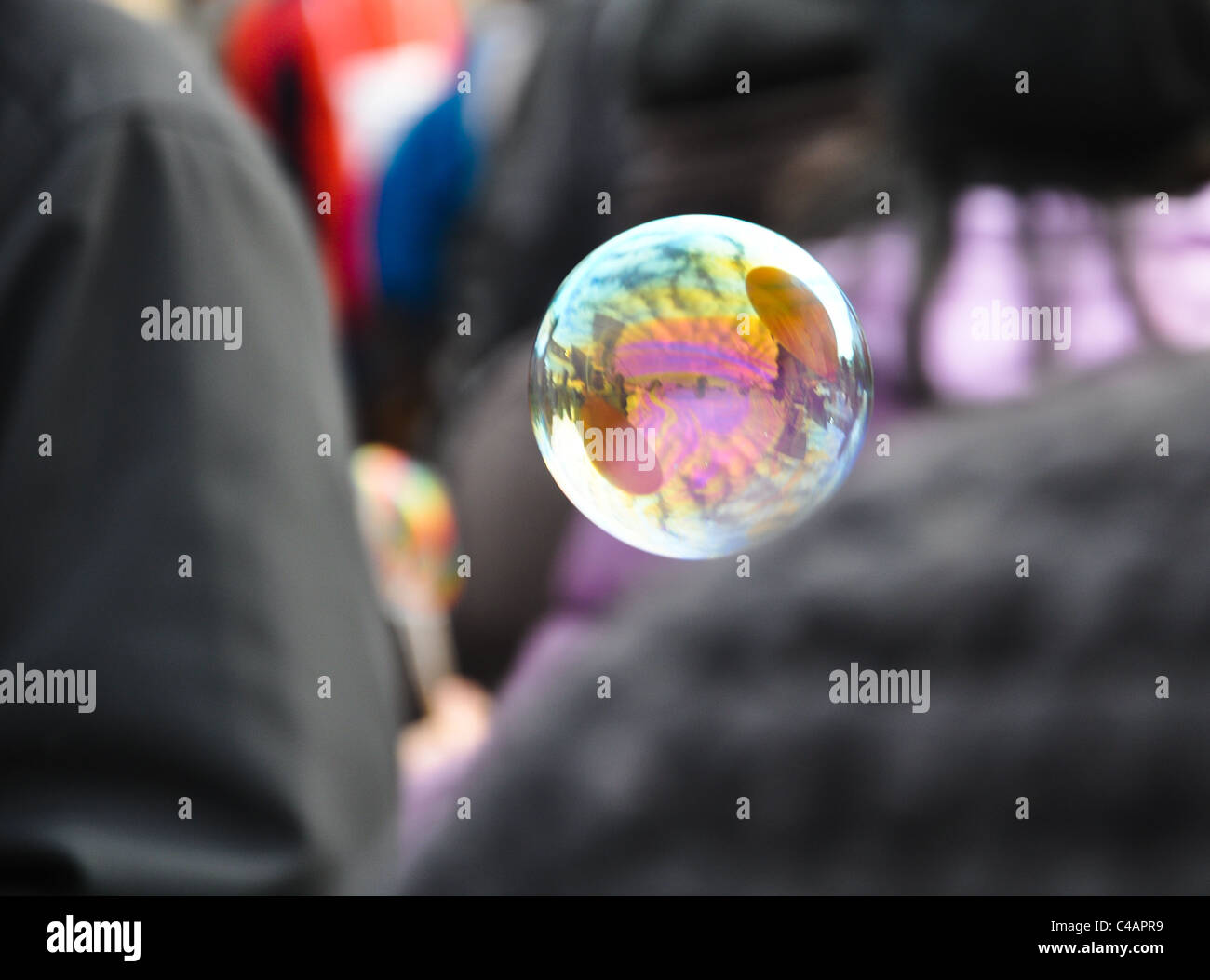 a lone fragile soap bubble is floating through a crowd Stock Photo