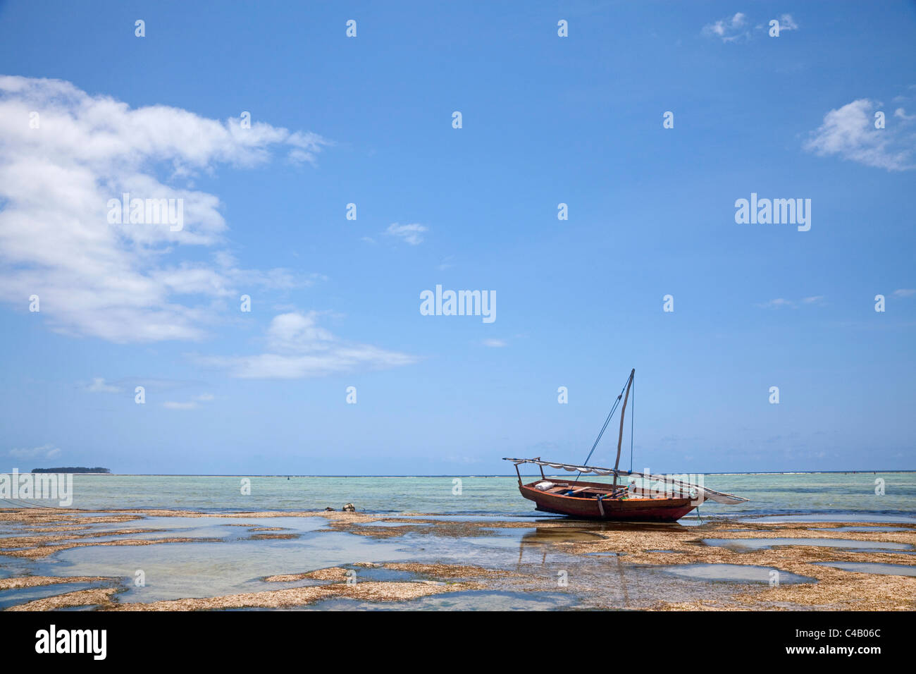 Zanzibar, Matemwe. A boat is stranded on the low tide, with Mnemba Island in the distance. Stock Photo