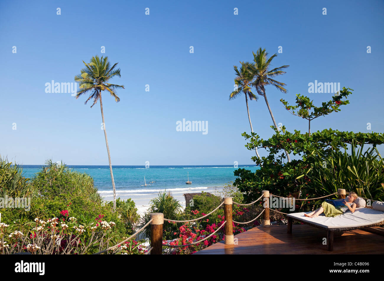 Zanzibar, Matemwe Bungalows. A guest relaxes on her sunbed, overlooking the private beach. MR. Stock Photo
