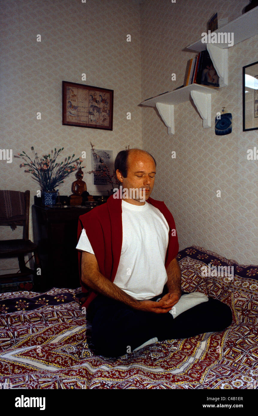 England Buddhist Meditating At Home In Lotus Position For Yoga Stock Photo