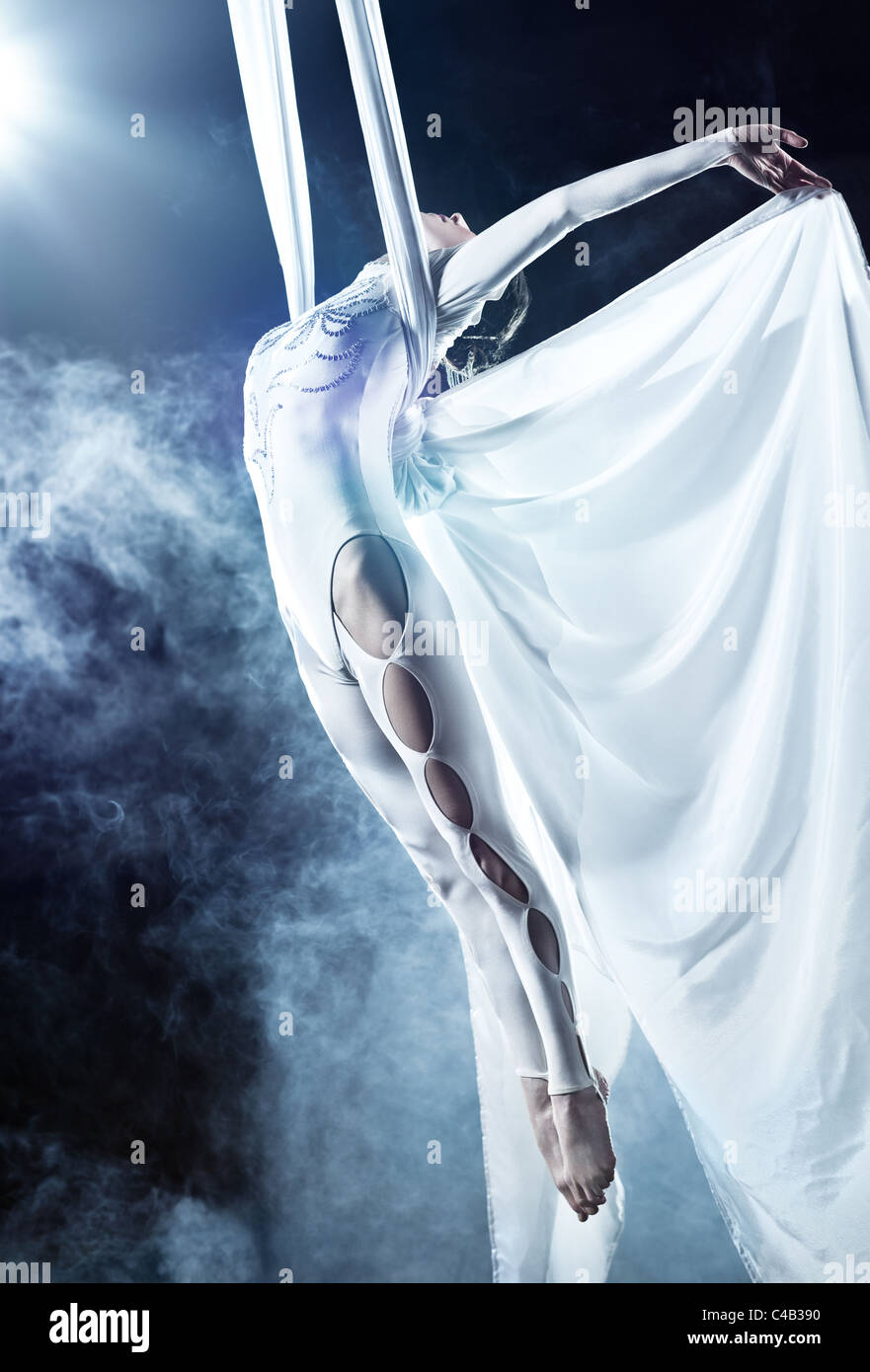 Young woman gymnast. On black background with smoke. Stock Photo