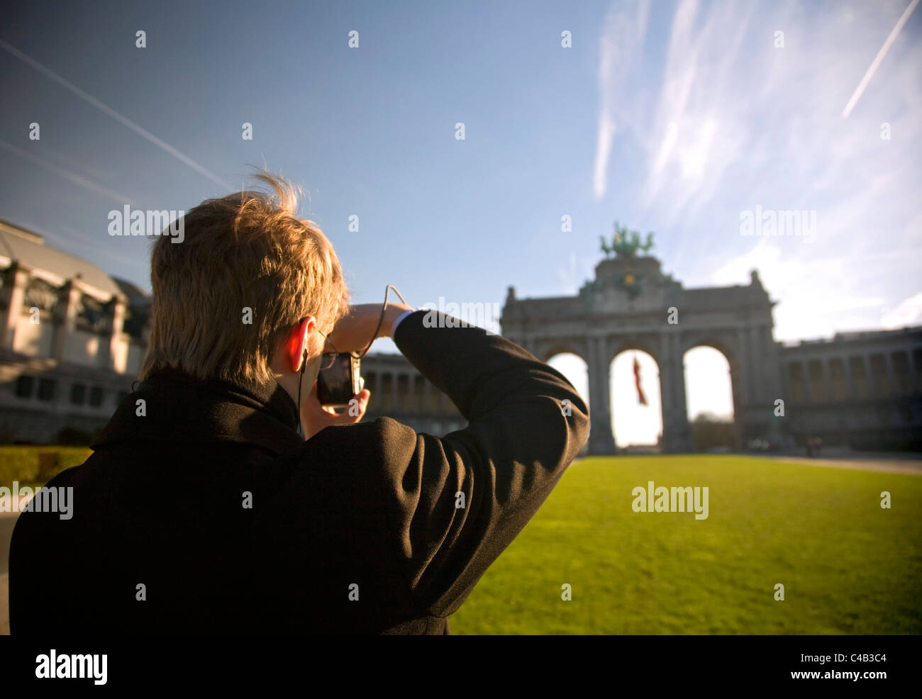 Brussels, Belgium; A young man taking a photo of the Triumphal Arch at the 'Parc du Cinquantenaire' on his portable camera Stock Photo