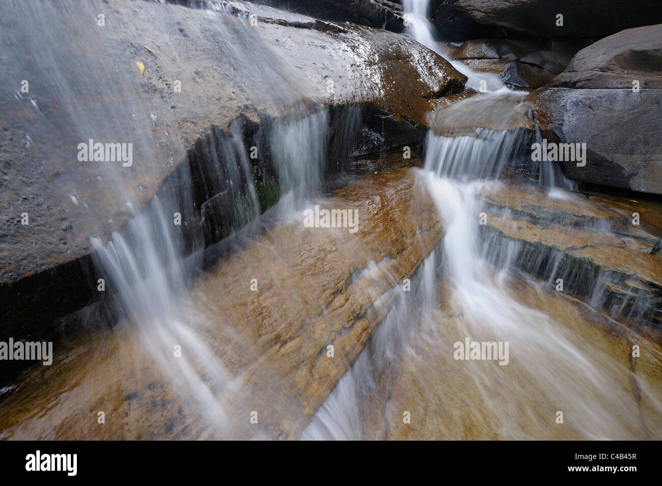 Long exposure of water cascading down over boulders in The Cascades, Mahai Valley, Drakensberg uKhahlamba National Park, Kwazulu Natal, South Africa Stock Photo