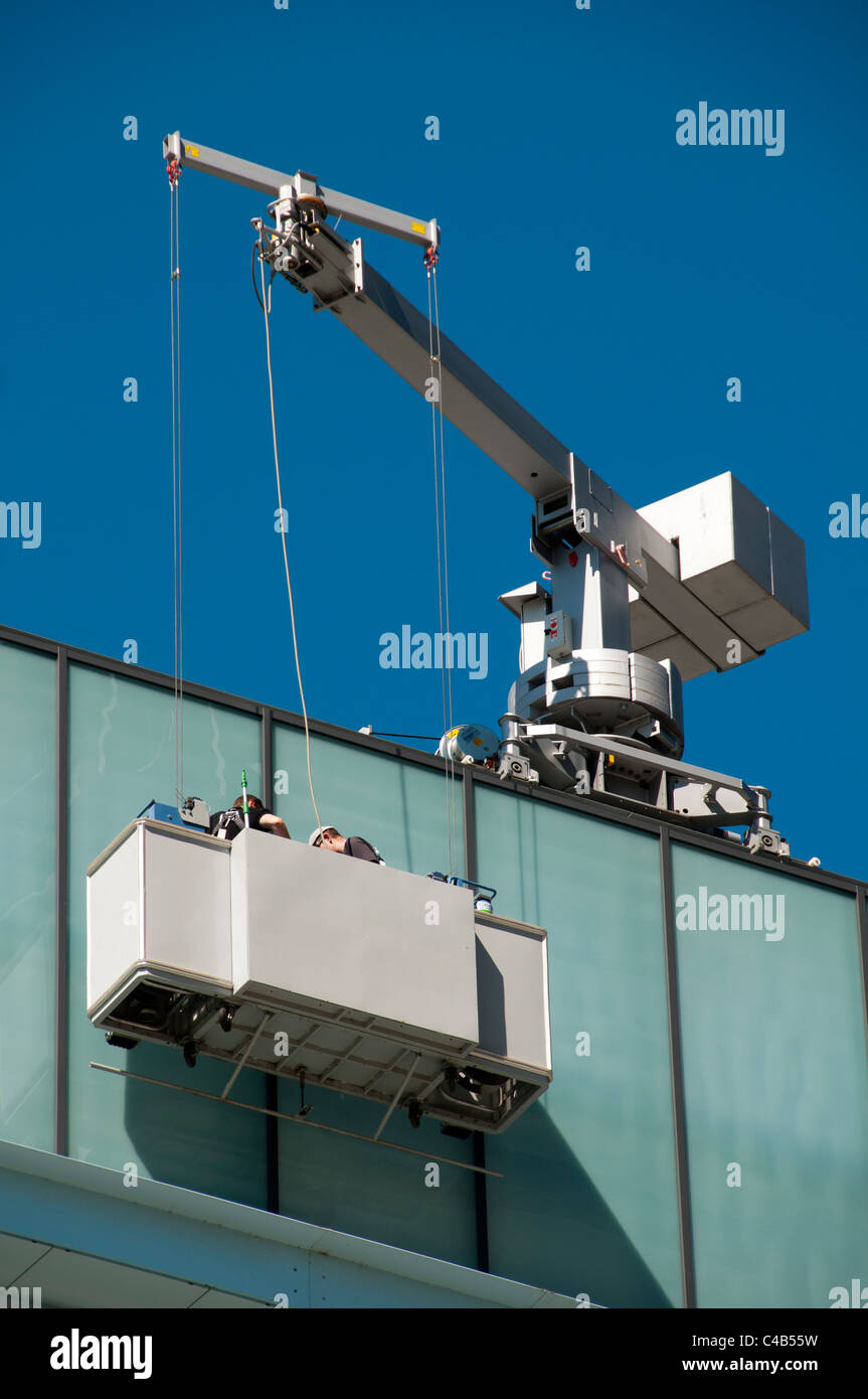 Workers on a suspended access platform at the MediaCityUK complex, Salford Quays, Manchester, England, UK Stock Photo
