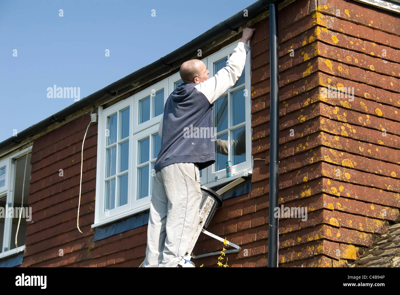 Installing A rated energy efficient replacement double glazed windows on an old house to improve energy efficiency Stock Photo