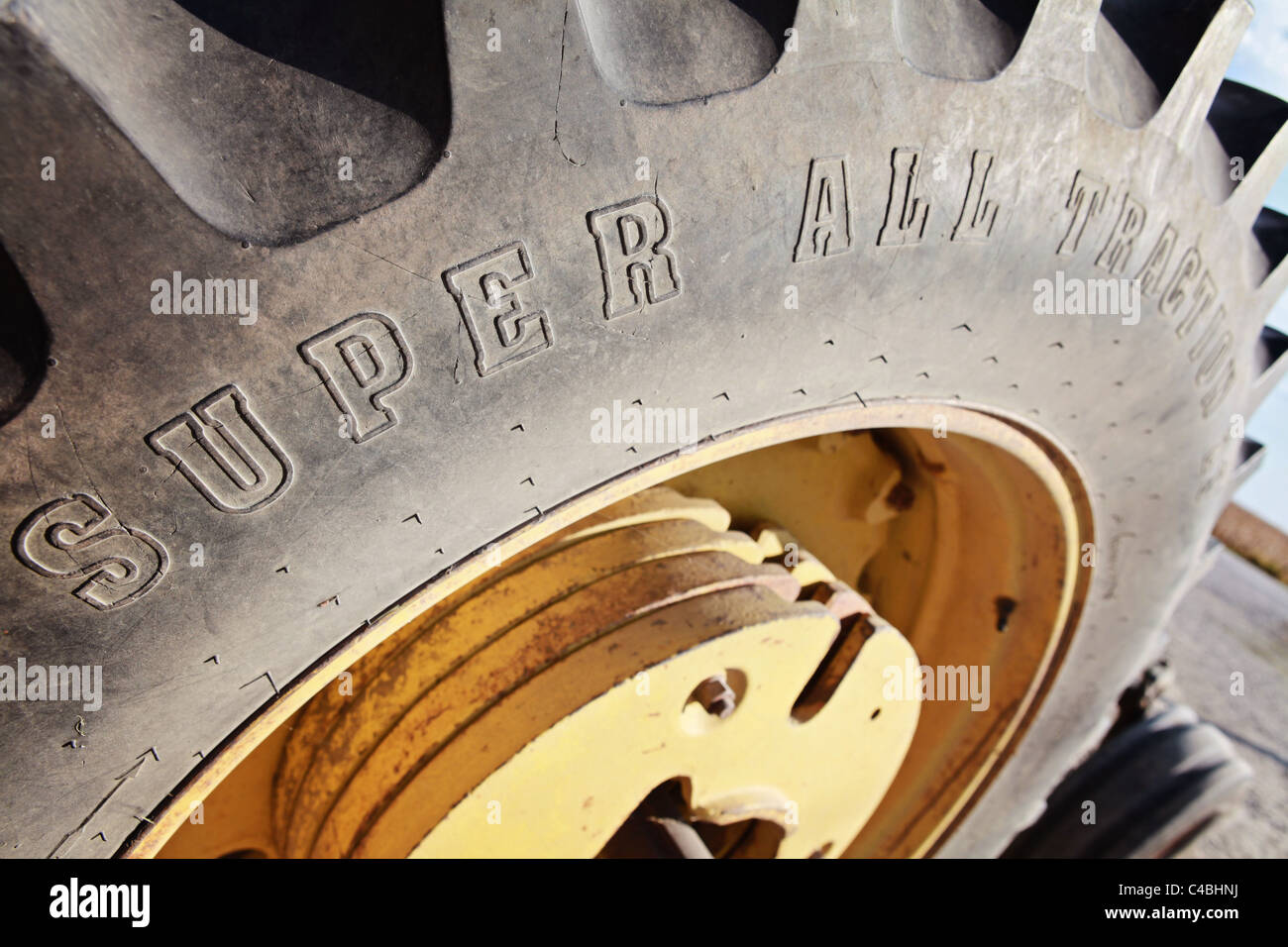 Large tractor tire with yellow rims and weights. Treaded super all