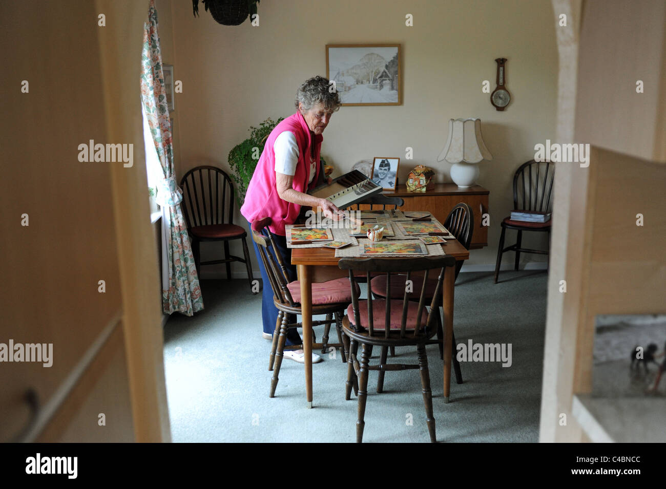 Female old age pensioner setting her dining room table at home for dinner UK Stock Photo