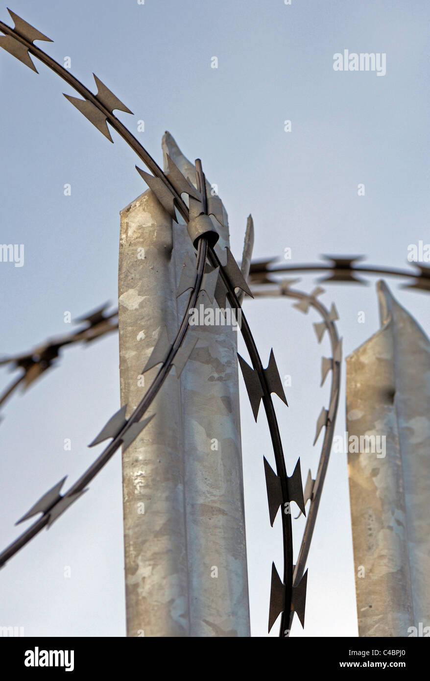 Concertina razor wire mounted onto galvanized steel  pointed fence. Stock Photo