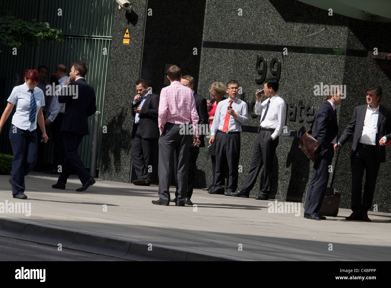 Smokers taking a break outside offices of 99 Bishopsgate central London, UK Stock Photo