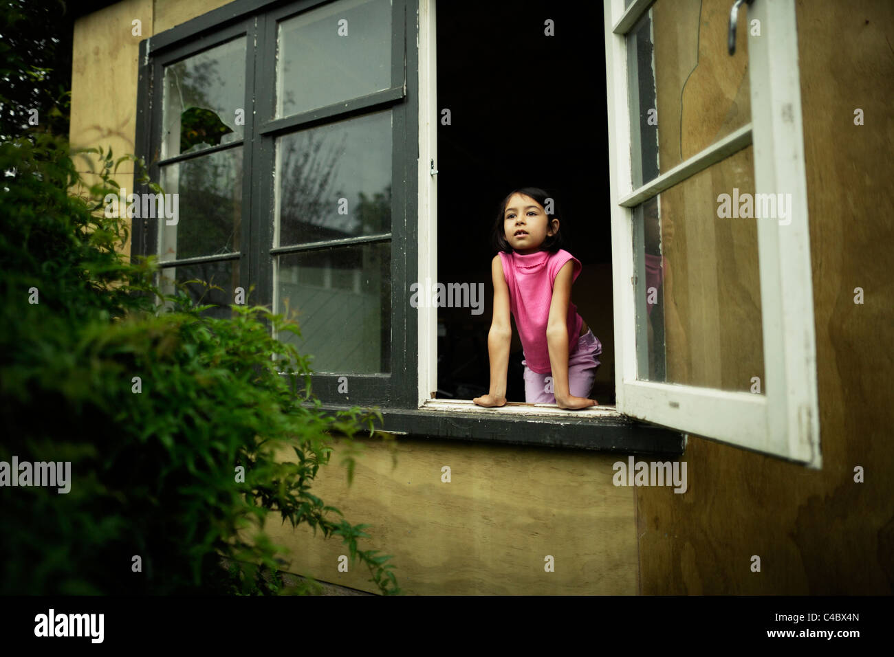 Girl looking out shed window Stock Photo