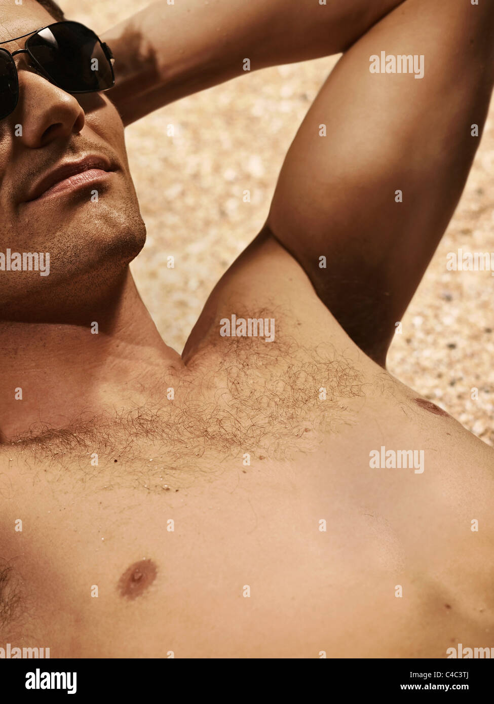 Bare-chested man sunbathing on beach Stock Photo
