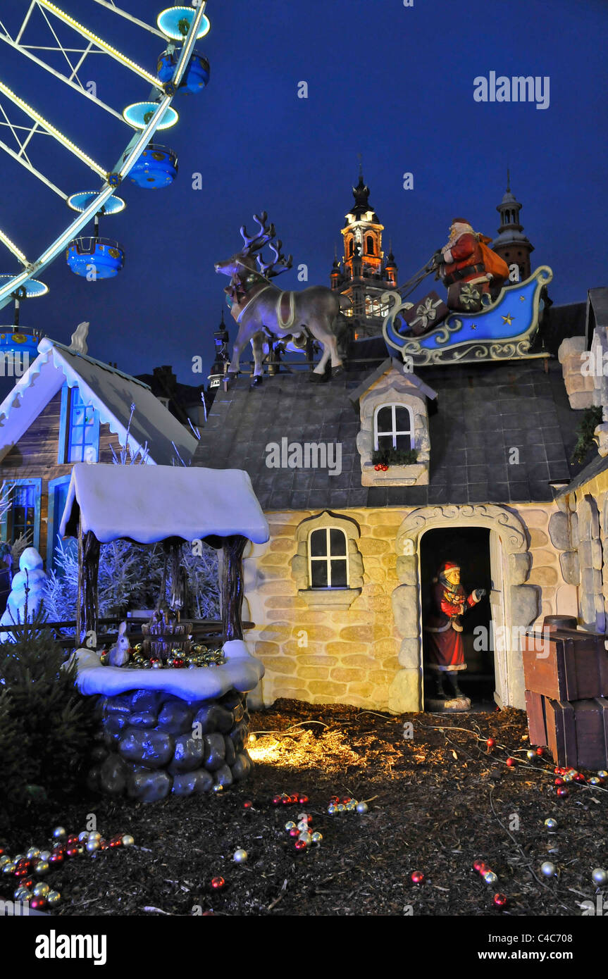 A portrait image showing a Yule Tide scene at a Christmas market in Lille France. Show Santa in his sleigh on roof of a house Stock Photo