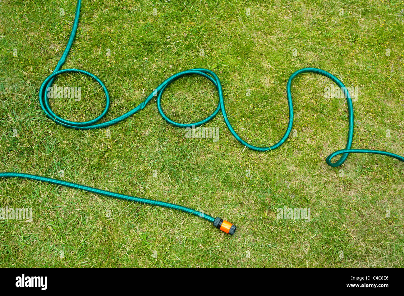 A water shortage usually leads to a hose pipe ban. The pipe is disconnected and laid out on a lawn, it reads as the word ban. UK Stock Photo