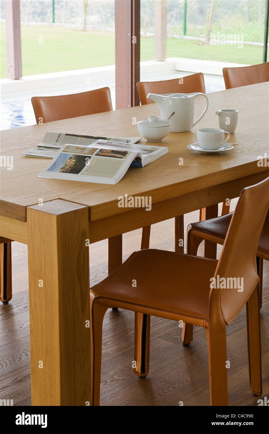 close-up of leather CAB chairs (by Bellini for Cassina) and oak dining table with open books and a cup of coffee Stock Photo