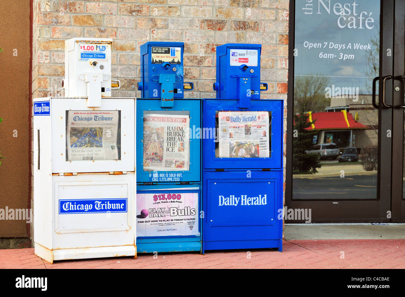 Newspaper vending boxes for the main Chicago daily newspapers sit outside a closed restaurant. Bartlett, Illinois, USA. Stock Photo