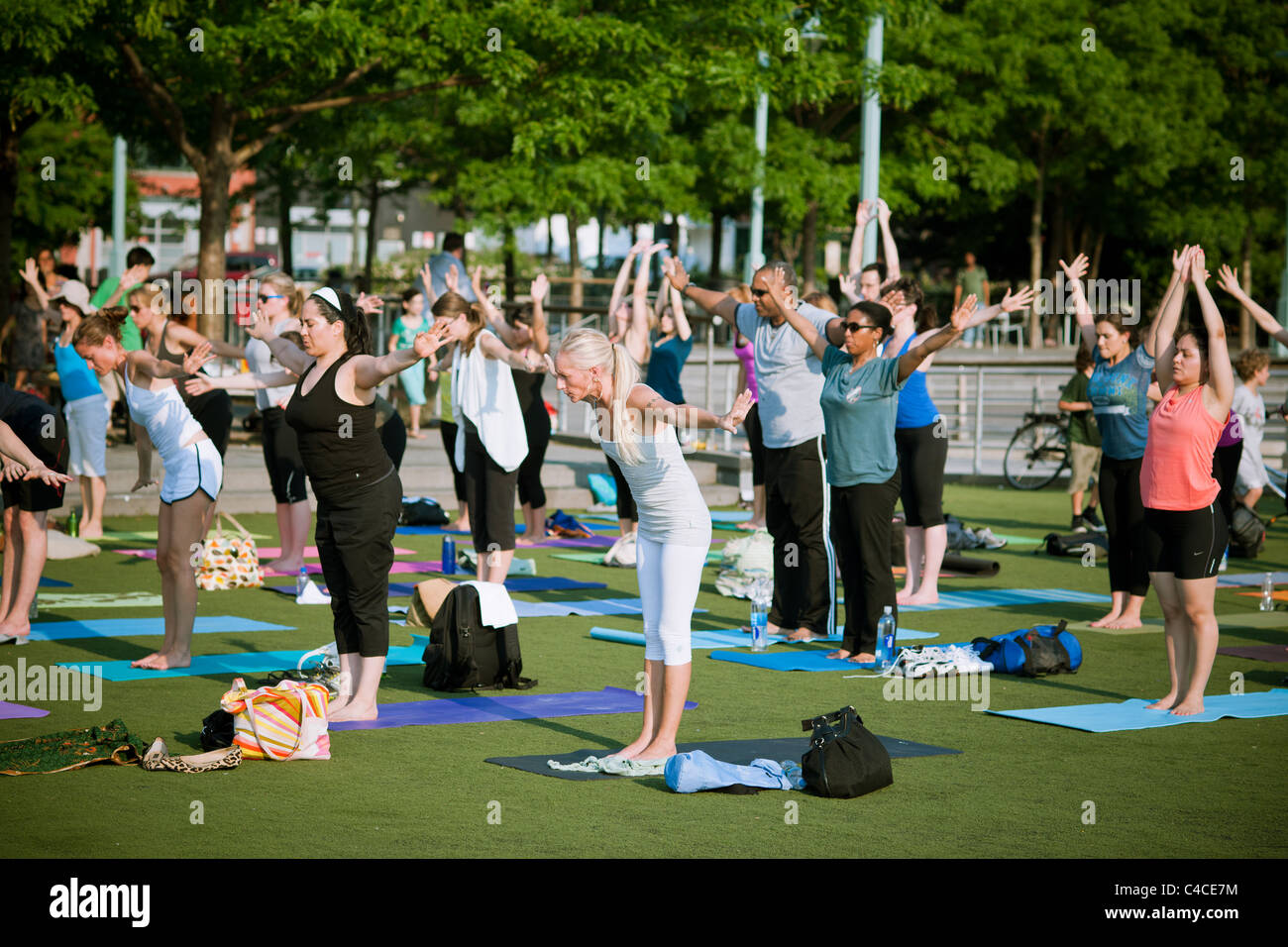 Yoga practitioners participate in a free afternoon yoga class given in in Hudson River Park in New York Stock Photo