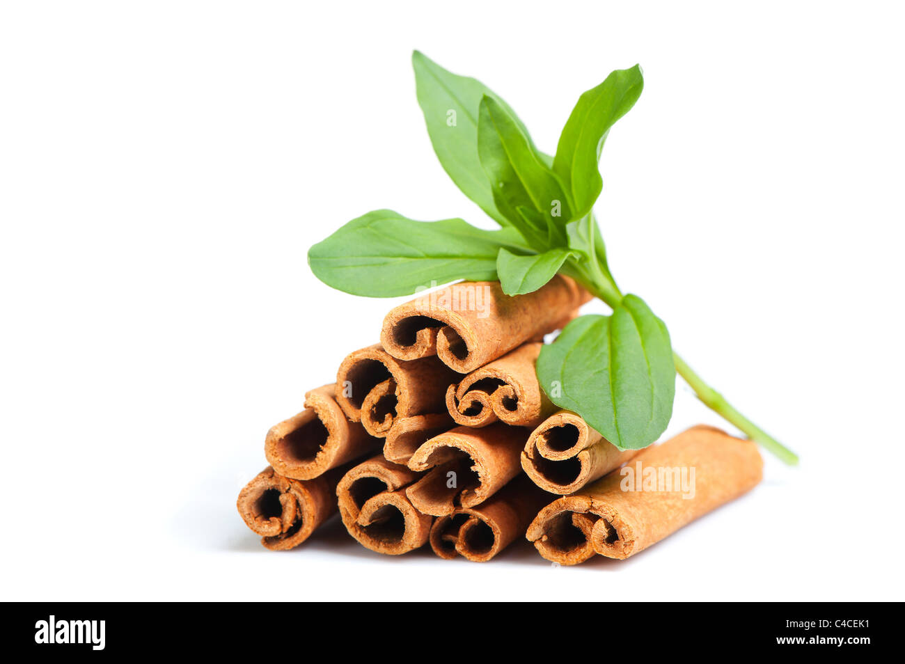 Cinnamon and green leaves. A heap of sticks of cinnamon on a white