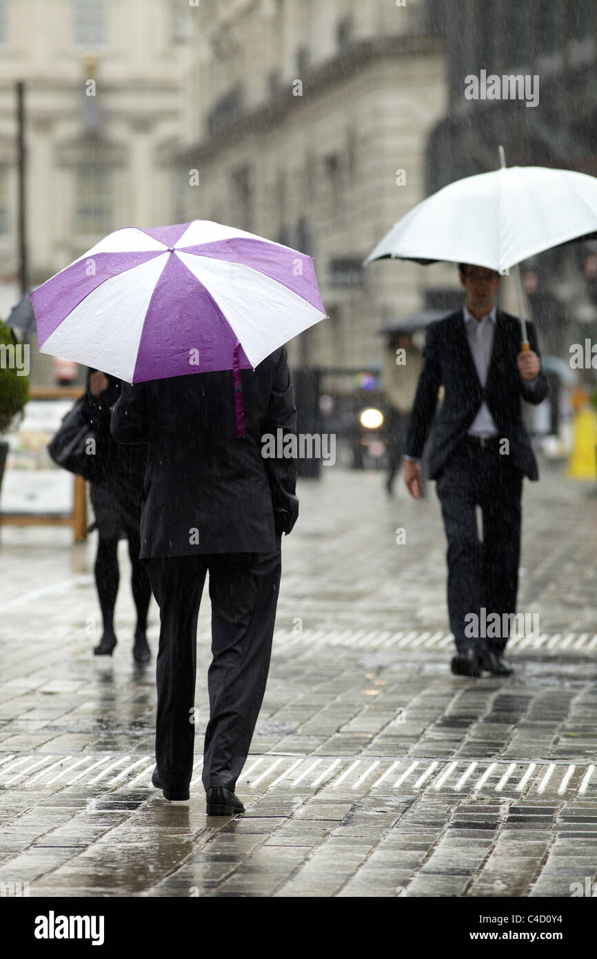 London City workers in rain with umbrellas in Queen Street, London