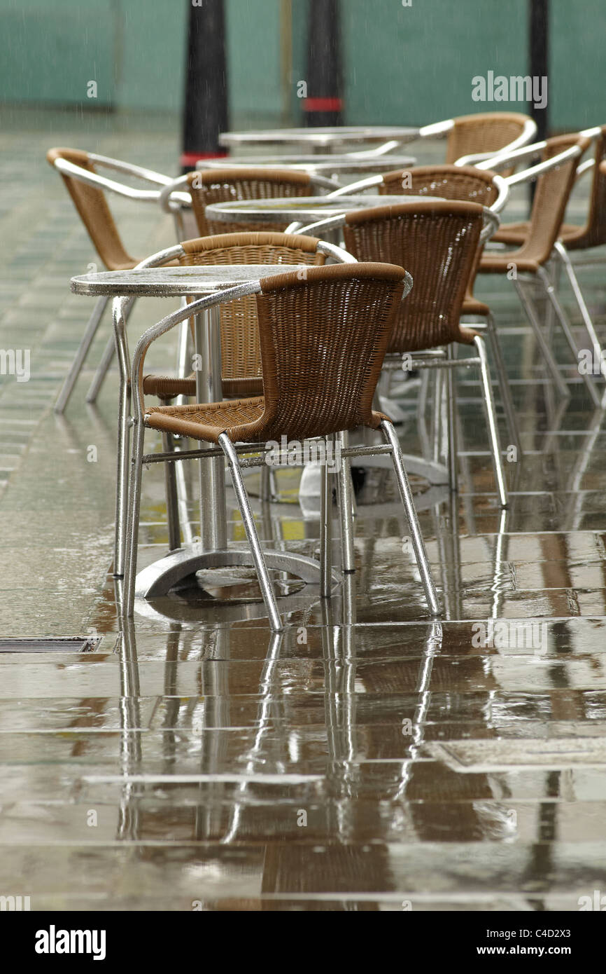 London cafe chairs and tables on the pavement in the rain. Shallow