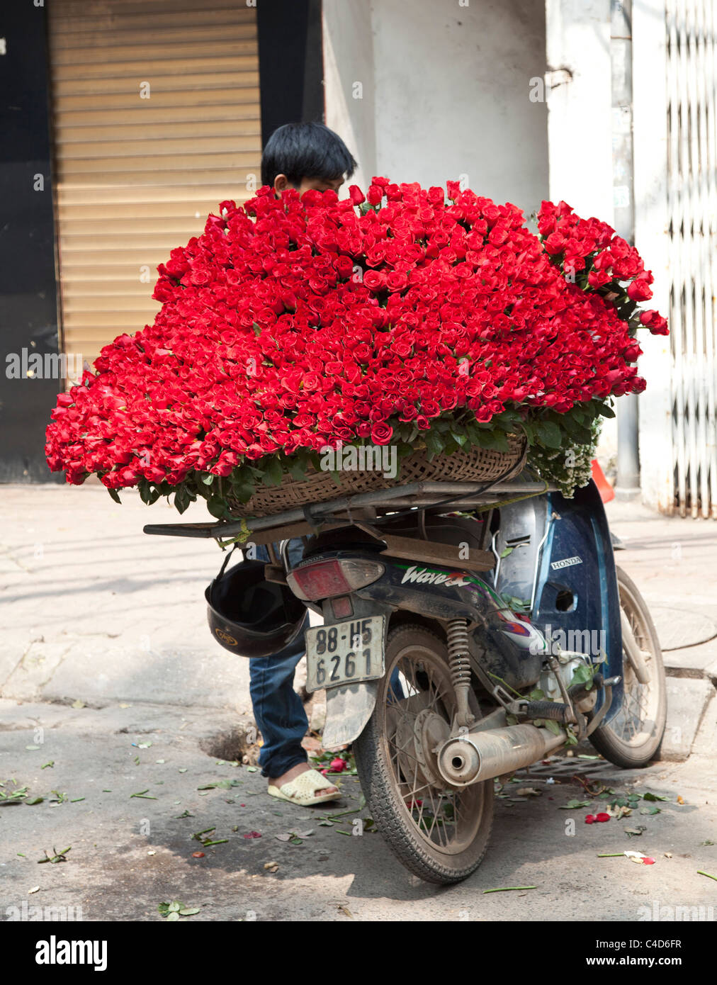 Street market seller with red roses for sale on the back of a motor cycle. Hanoi, Vietnam. motor bike Stock Photo