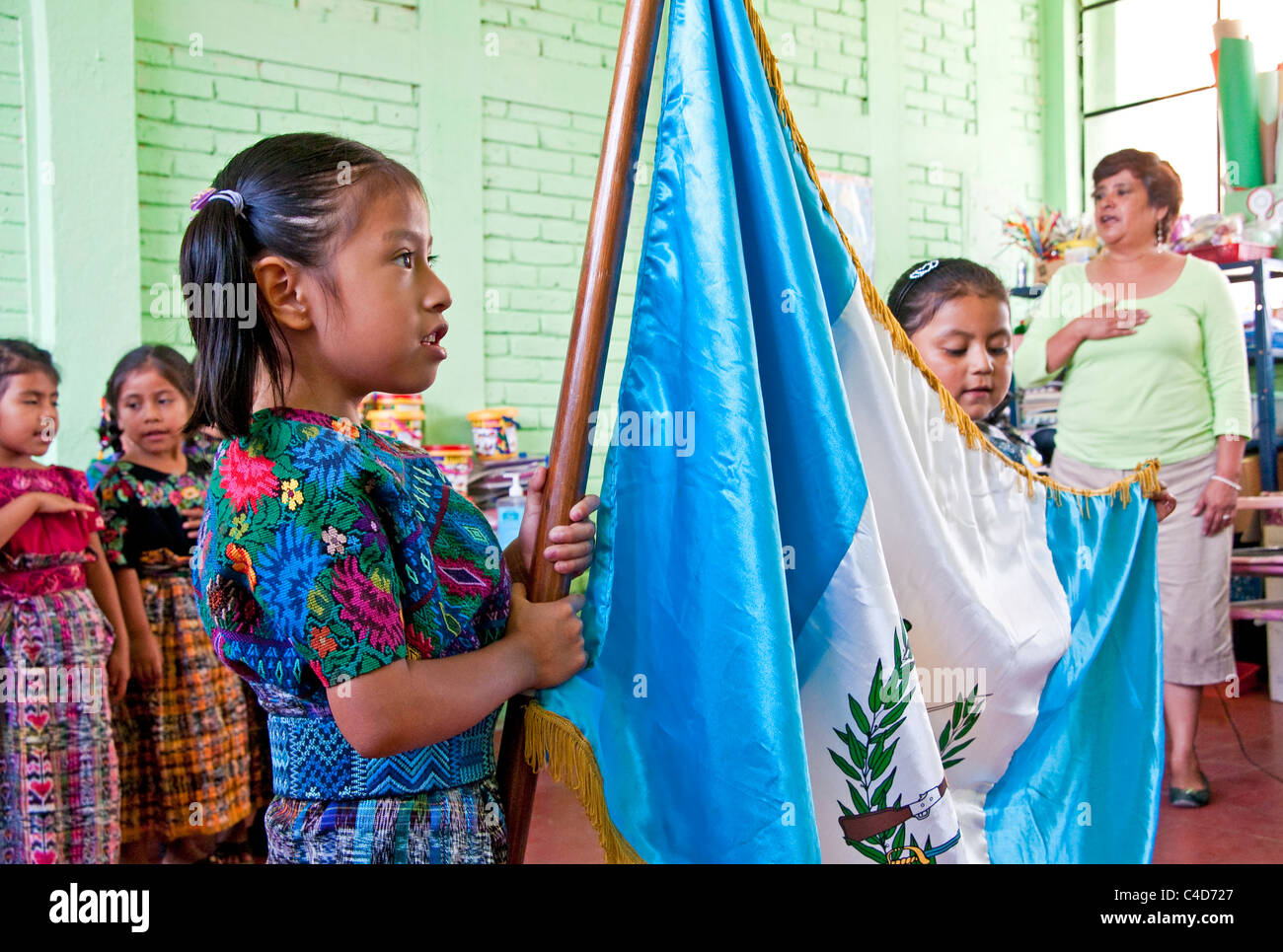 Teacher leading kindergartner class of Mayan children in pledge of allegiance to Guatemalan flag in village school near Antigua Stock Photo