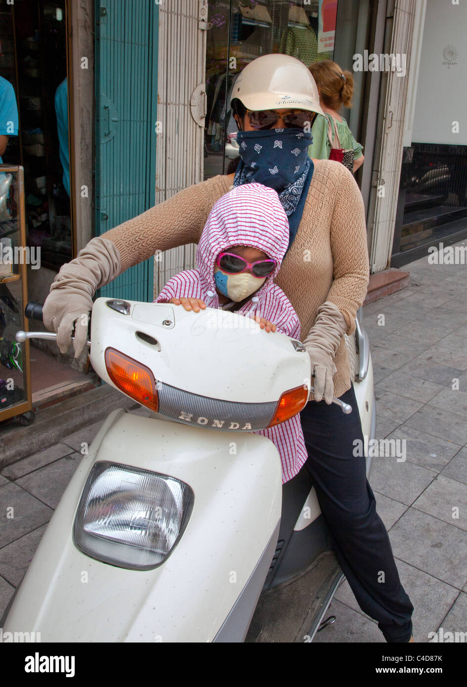 Mother and child on motorbike, wearing masks because of the air pollution, Hanoi, North Vietnam Stock Photo