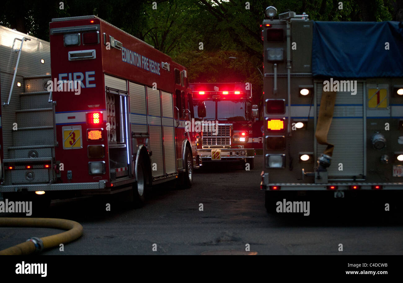 Three fire rescue trucks with emergency lights active fighting fire ...