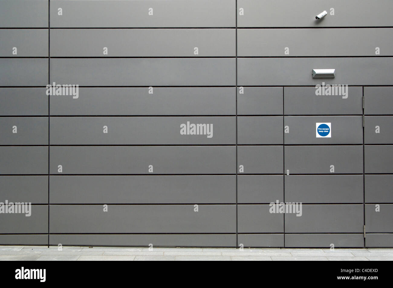 CCTV security camera above hidden emergency exit door on office wall