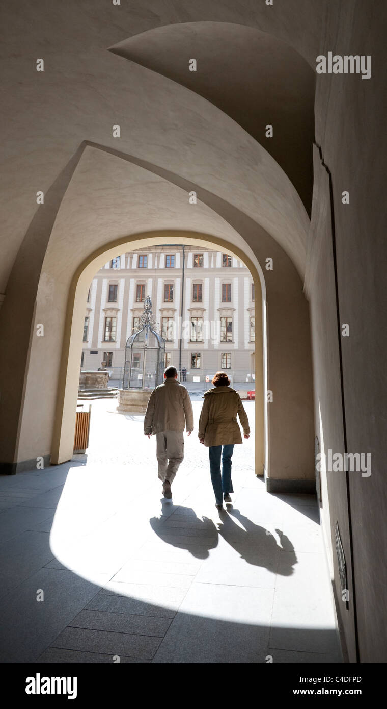 A couple silhouetted by the spring sunshine walking through an arch at the President's Office at Prague Castle Stock Photo