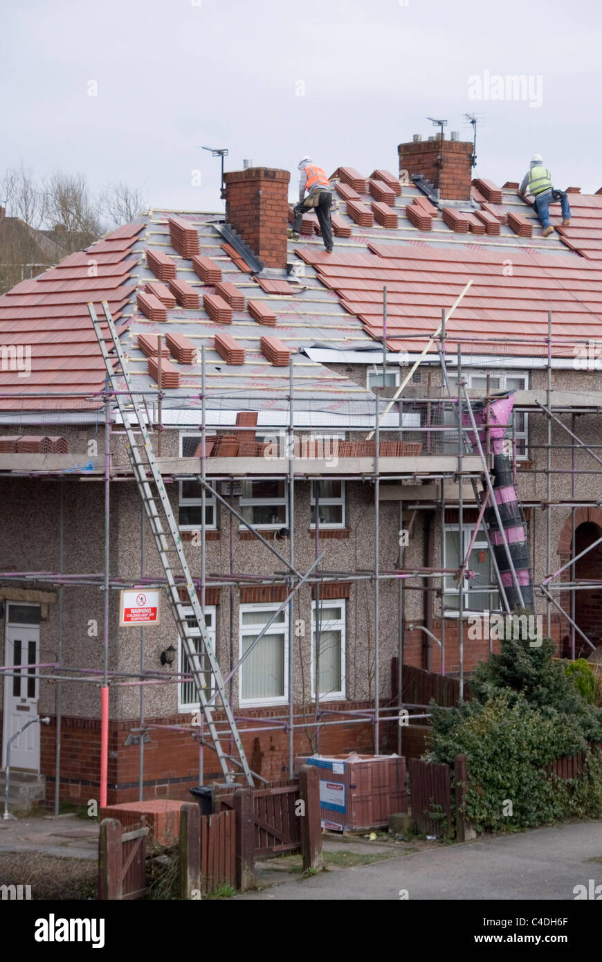 Two Men on Roof of House Laying New Roof Tiles, Re Roofing ACIS Properties,  Hastilar Road South, Sheffield, March 2011 Stock Photo - Alamy