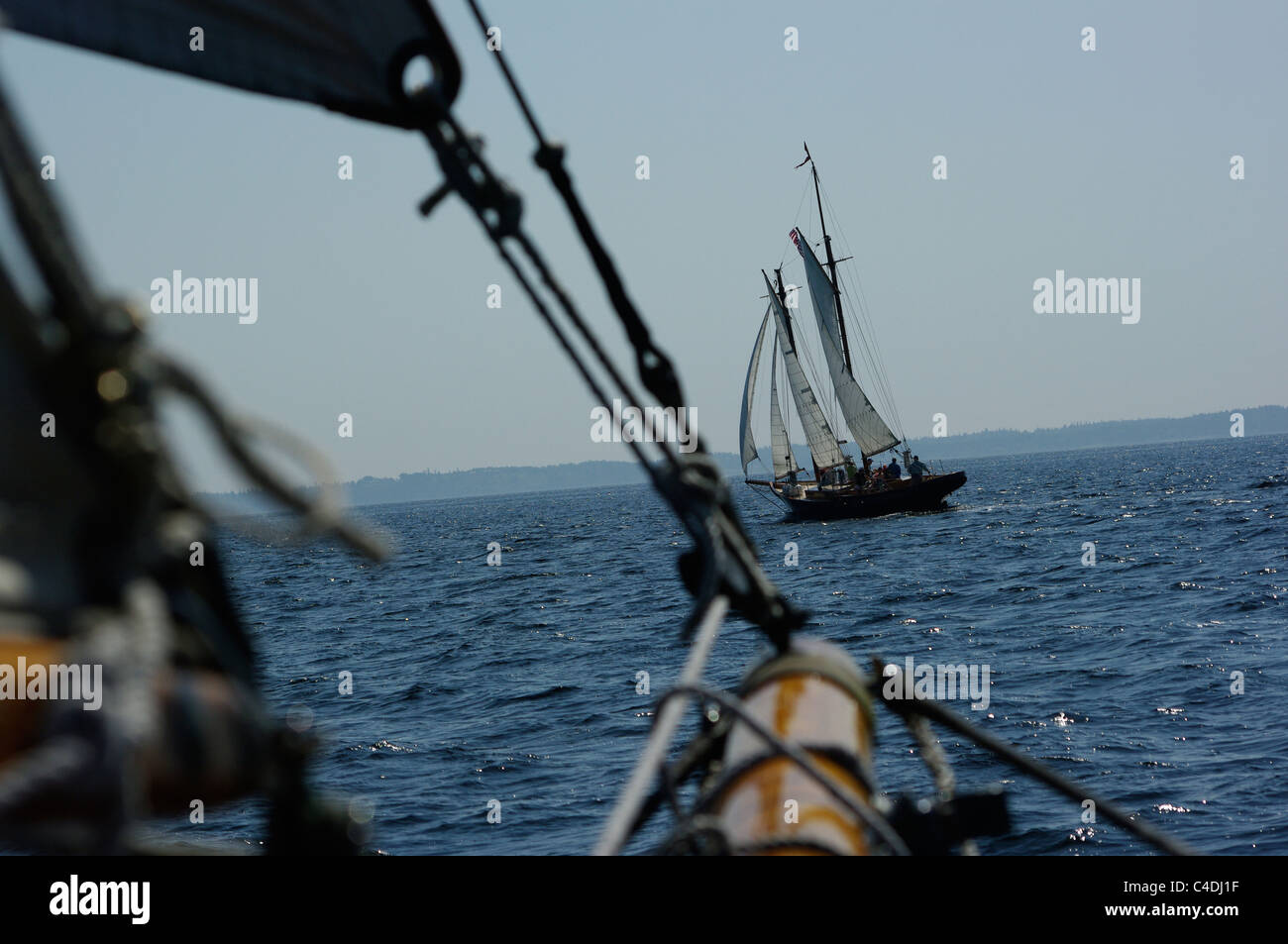 A sailing yacht and a wooden schooner chase each other across the