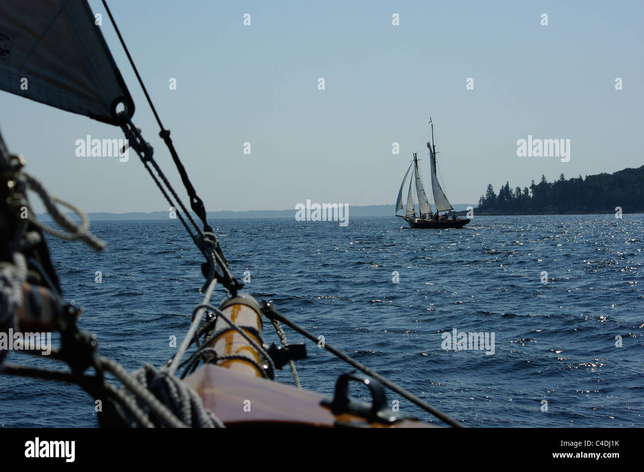 A sailing yacht and a wooden schooner chase each other across the