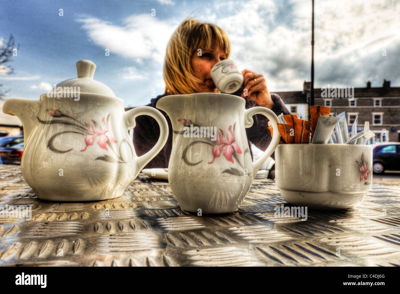 Woman, lady drinking a typical English cup of tea with tea pot and milk