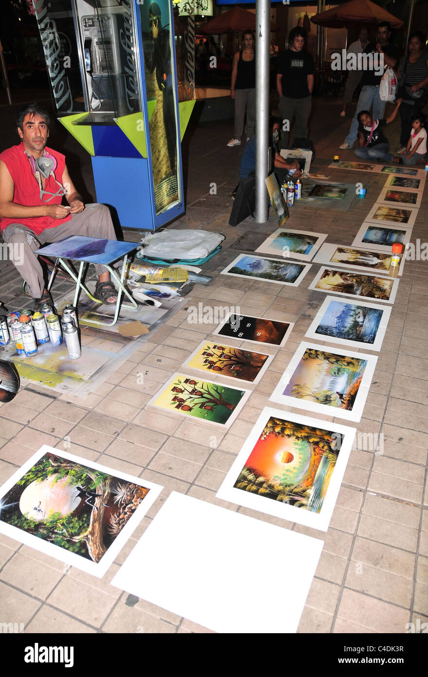 Night-time portrait of spray paint artists and paintings laid out on paving tiles, Paseo Sarmiento. Mendoz, Argentina Stock Photo