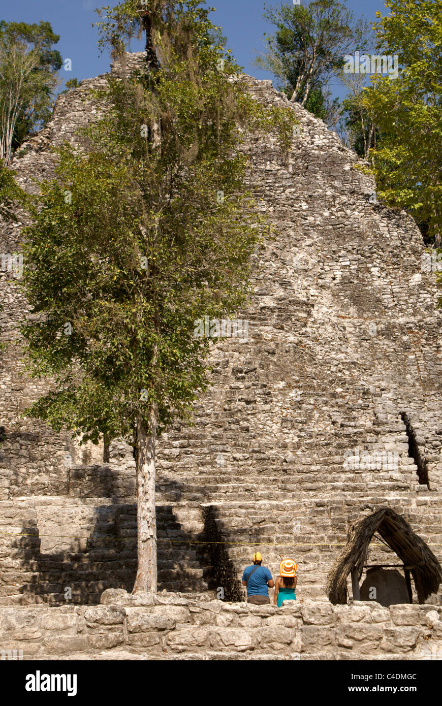 Tourist couple looking up at La Iglesia or Church pyramid in the Cobá Group at the Mayan ruins of Cobá, Quintana Roo, Mexico Stock Photo